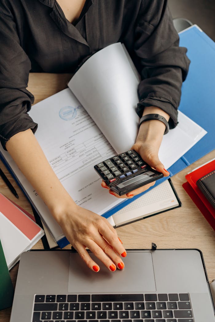 person holding black calculator while using laptop 8296981